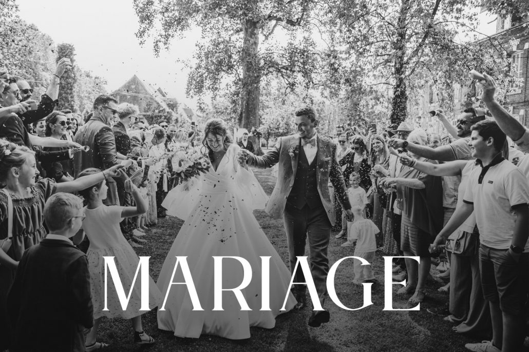 Photo de mariage couple à la sortie de la cérémonie acclamé par les invités